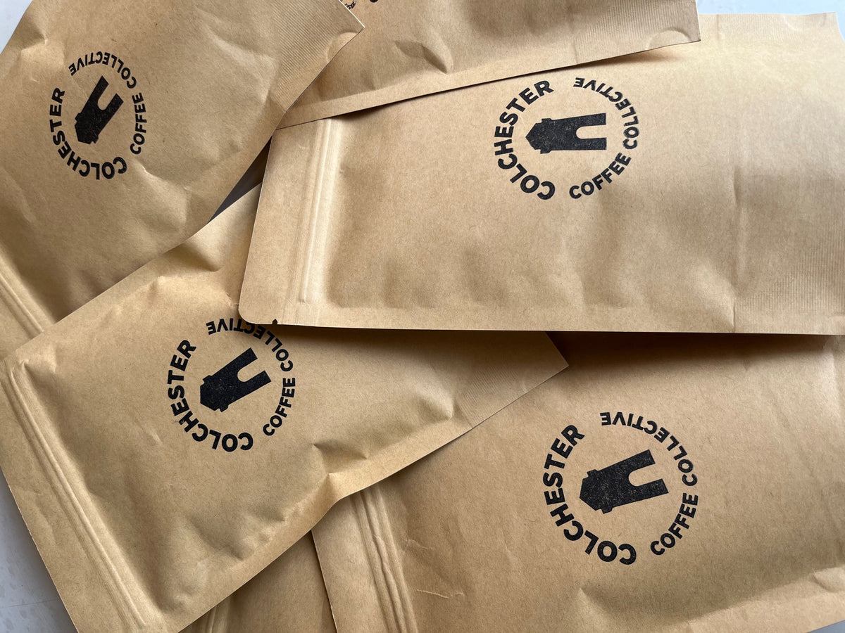 Kraft coffee bags stamped with the Colchester Coffee Collective roundel